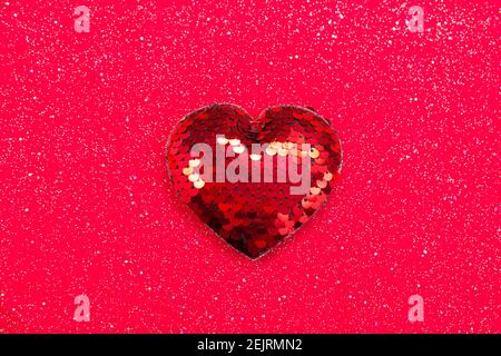 Red heart with sequins on red fabric background. Top view, copy space, selective ocus Stock Photo