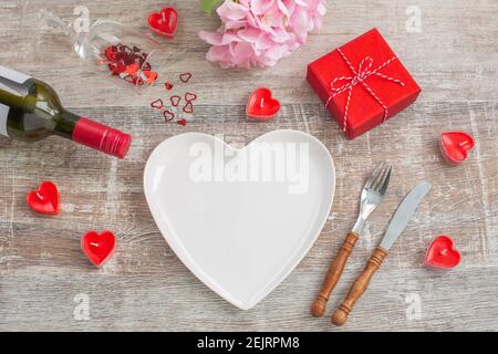 Red wine bottle and love gift box, candles, flowers on wooden background. Valentines day. The concept of holidays and love. Flat lay Stock Photo