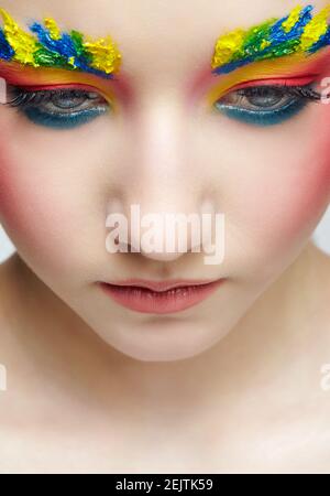 Close-up teenager girl face portrait with unusual face art make-up . Paint on brows. Stock Photo