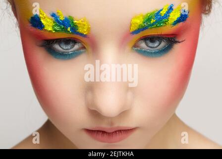 Close-up teenager girl face portrait with unusual face art make-up . Paint on brows. Stock Photo