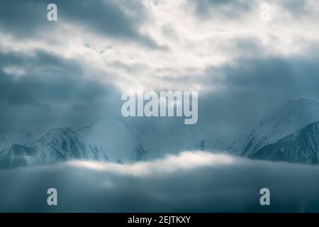 Mountains covered with snow between fog clouds with bright sunrays shining through, Mieminger Plateau, Tirol, Austria Stock Photo