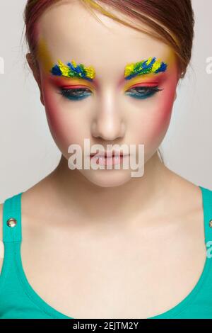 Close-up teenager girl face portrait with unusual face art make-up . Paint on brows and hair. Stock Photo