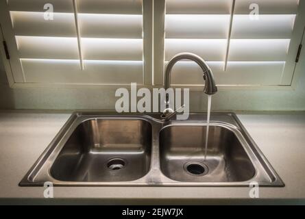 sink in a kitchen with running tap water Stock Photo