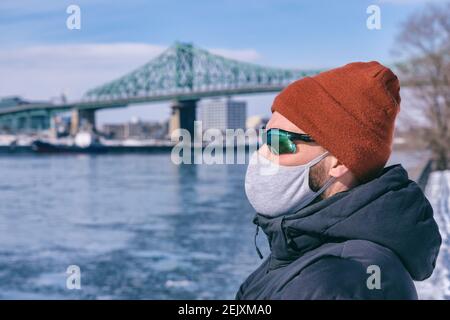 Young man wearing protective mask for Coronavirus protection and Montreal Jacques Cartier Bridge in background Stock Photo
