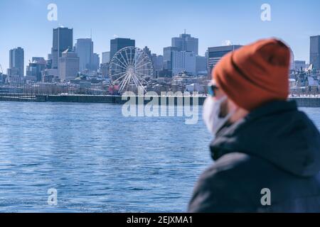 Young man wearing protective mask for Coronavirus protection looking at Montreal skyline Stock Photo