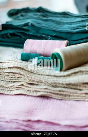 Vertical textile background. Cotton muslin fabrics of different colors and spools of thread of the same color. Stock Photo