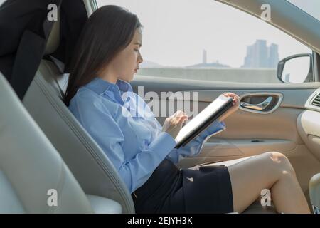 Businesswoman inside a car using a tablet for working. Stock Photo