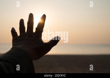 Hand reach out to sunset sky beach sand nature background. Relax and rest in vacation time. Stock Photo