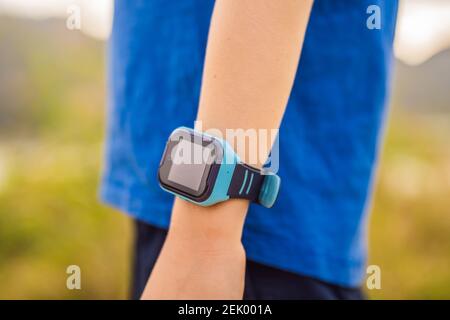 Boy uses kids smart watch outdoor against the background of the garden Stock Photo