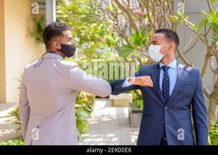 Two African businessman wearing medical mask while greeting with elbow bump greeting. Social distance concept during the coronavirus epidemic. Stock Photo