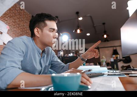 Architect reading building and  drawing outlay construction plan as guide for builders with details on computer. Engineer design and writing blueprint Stock Photo