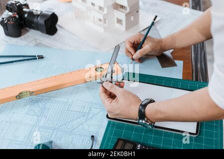 Engineering hands hold vernier caliper working and checking drawing blue print scale on workplace.  Architecture, engineering, business and civil conc Stock Photo