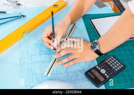 engineers holding a pen pointing to a building and  drawing outlay construction plan as guide for builders with details. Engineer design and writing b Stock Photo
