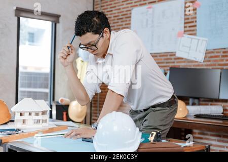 industry manager, engineer, businessman reading and checking blueprint, drawing plan in the room in office. Stock Photo