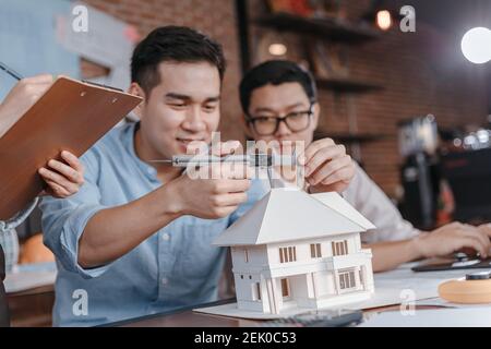 Engineering hands hold vernier caliper working and checking house model scale between meeting with businessman and businesswoman. Architecture, engine Stock Photo