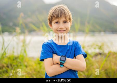 Boy uses kids smart watch outdoor against the background of the garden Stock Photo