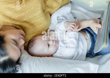 mother and her son reading book in a bed before sleep. Familly story telling concept. Stock Photo