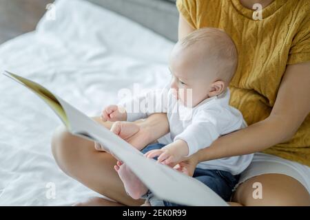 mother and her son reading book in a bed before sleep. Familly story telling concept. Stock Photo