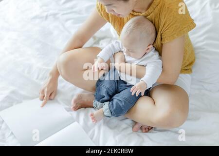 mother and her son reading book in a bed before sleep. Familly story telling concept. Stock Photo