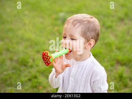Happy little kid blowing soap bubble in school garden. Stock Photo