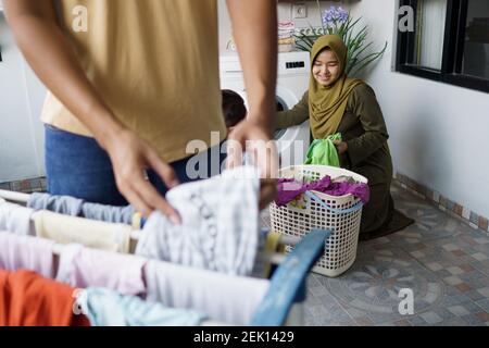 happy young muslim woman and her husband doing laundry together at home Stock Photo