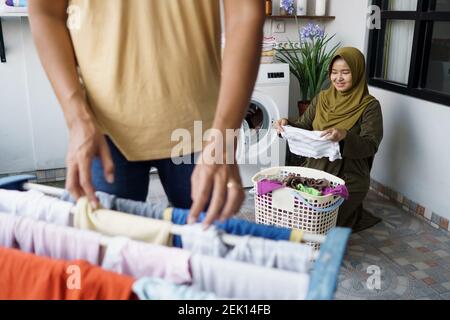 happy young muslim woman and her husband doing laundry together at home Stock Photo