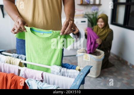 happy young muslim woman and her husband doing laundry together at home Stock Photo