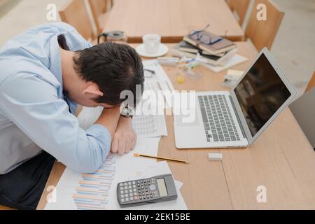 handsome businessman sleepy before working with laptop at desk in office. Working late night and start working early in the morning. Stock Photo