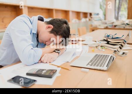 handsome businessman sleepy before working with laptop at desk in office. Working late night and start working early in the morning. Stock Photo