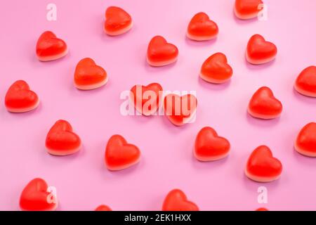 Many red tasty heart shape gummy candies on pink background. sweets background. Top view. Pattern Stock Photo