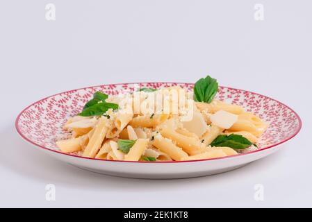 Selective focus and close up of freshly cooked pasta with cheese and herbs on a beautiful plate on a light background. Pasta and tasty food concept. Stock Photo