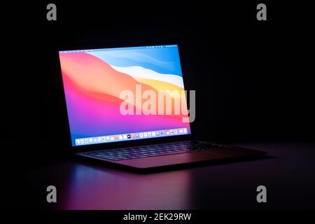 The new MacBook Air with Apple's M1 chip and the latest macOS Big Sur isolated on a desk in the dark. Stock Photo