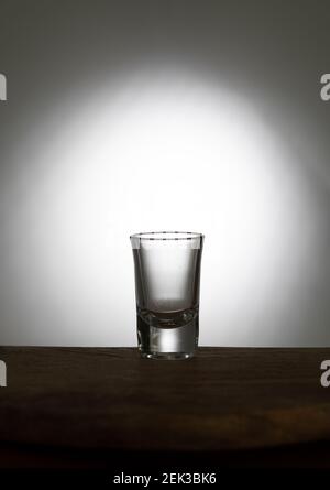 Vodka on an old wooden table as detailed close-up shot. Transparent glass with liquid Stock Photo