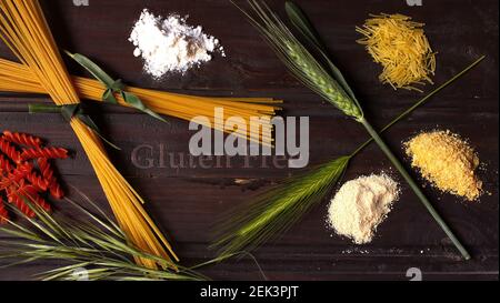 Healthy food concept, various types of refined flours and gluten-free pasta on a dark wooden background with several ears of wheat and green barley Stock Photo