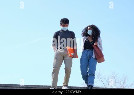 Young latin couple wearing protective face mask walking down into the train station. New normal in the university campus. Stock Photo