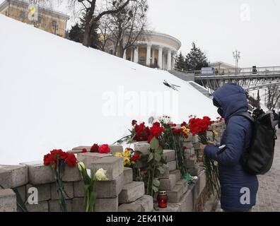 Non Exclusive: KYIV, UKRAINE - FEBRUARY 20, 2021 - A woman lays red carnations at the portrait of the perished Euromaidan activist on the Alley of the Stock Photo