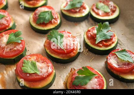 Oven baked zucchini snack with tomato, cheese and parsley garnish, vegetarian mini pizza for a healthy low carb diet, close up with selected focus and Stock Photo