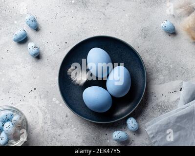 blue eggs and feathers in dark blue bowl Stock Photo