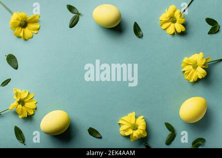 yellow eggs and flowers on green paper background Stock Photo