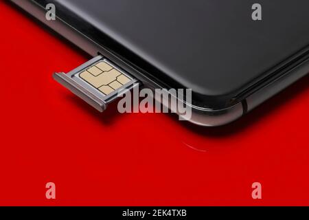 Close up of a smart phone and sim card on red background. Stock Photo