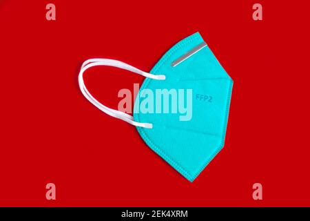 Side view of green FFP2 n95 protective face mask, coronavirus prevention. Isolated on red background. Stock Photo
