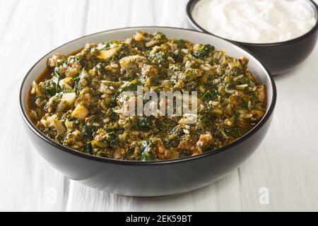 Delicious lunch beef stew with spinach, rice and onions close-up in a bowl on the table. horizontal Stock Photo