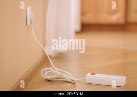 White extension into power outlet indoors. Photo of empty extension cord at home Stock Photo
