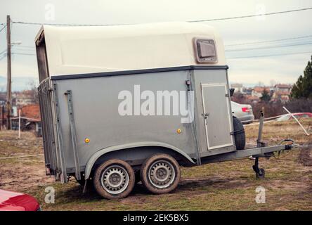 Grey horse transportation van with muddy tyres parked outside of the ranch during the day Stock Photo