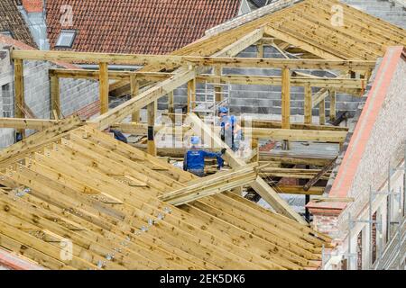 Workers roofers builders working on roof structure on construction site, Kuldiga, Latvia Stock Photo