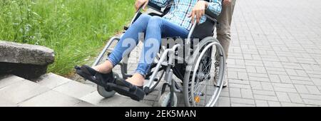 Man lift disabled person with stroller up stairs in city. Stock Photo