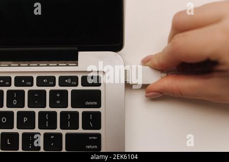 Femle hand inserting white USB flash drive into computer laptop Stock Photo