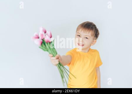 Boy holding a bouquet with tulips in their hands. Children congratulate on the holiday. Stock Photo