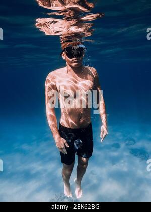 Male free diver glides underwater in blue ocean in Hawaii. Sporty man close up Stock Photo