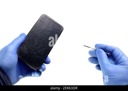An electronics repairman holds a broken phone and a screwdriver on a white background. Gloved hands with tools Stock Photo
